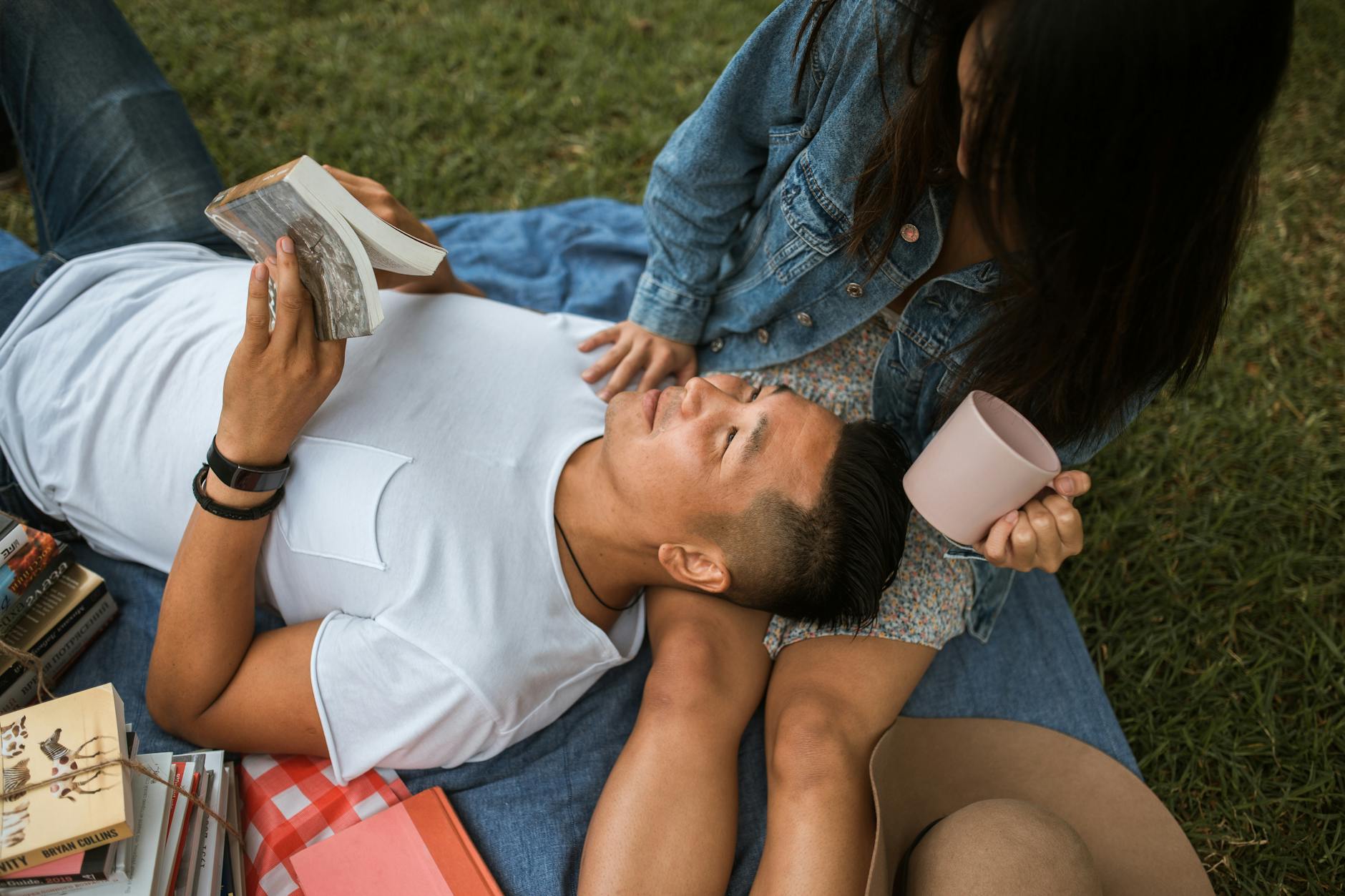 A couple relaxing outdoors on a blanket, reading slow living books and enjoying calm moments