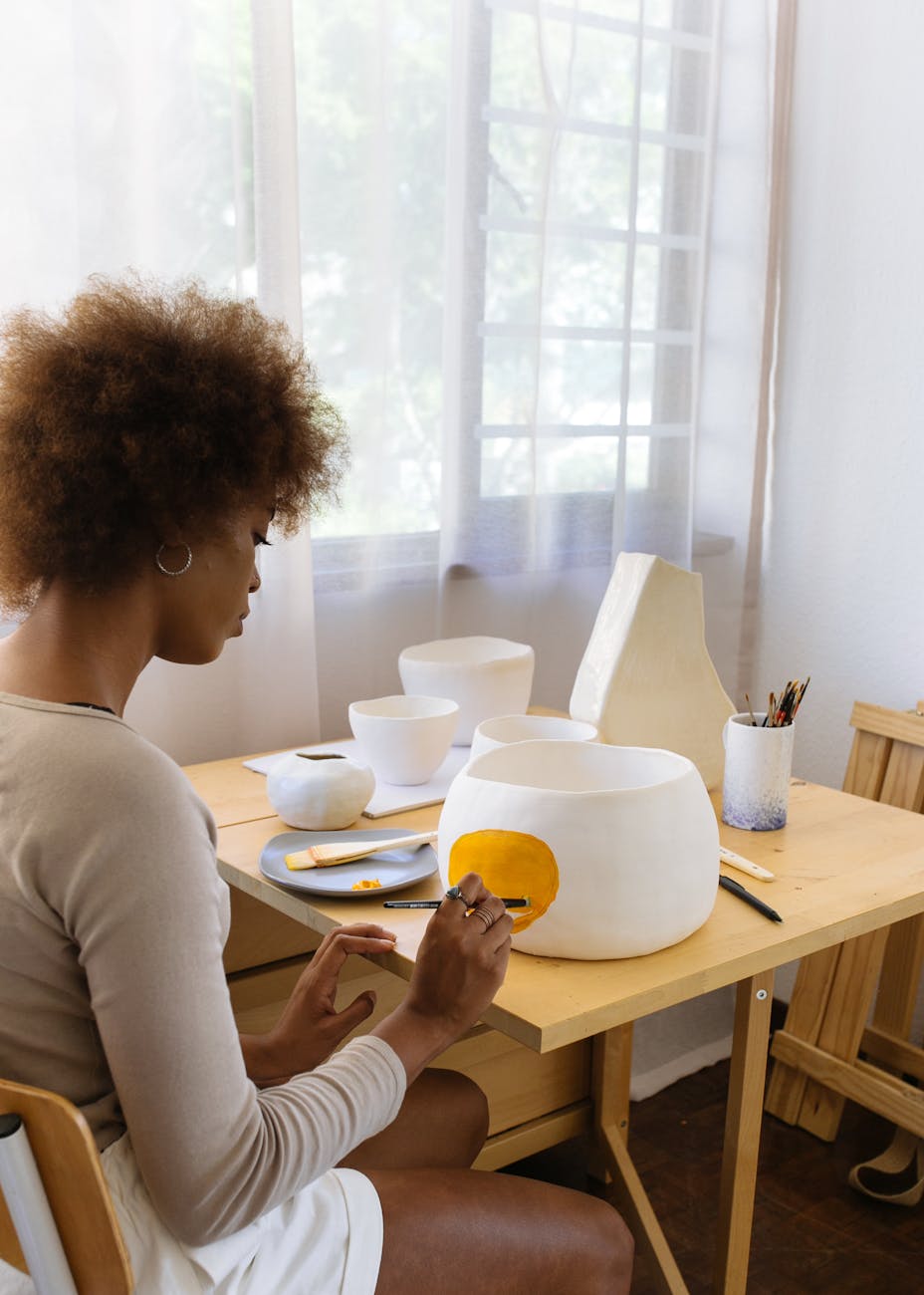 concentrated black female ceramist paining on handmade clay bowl